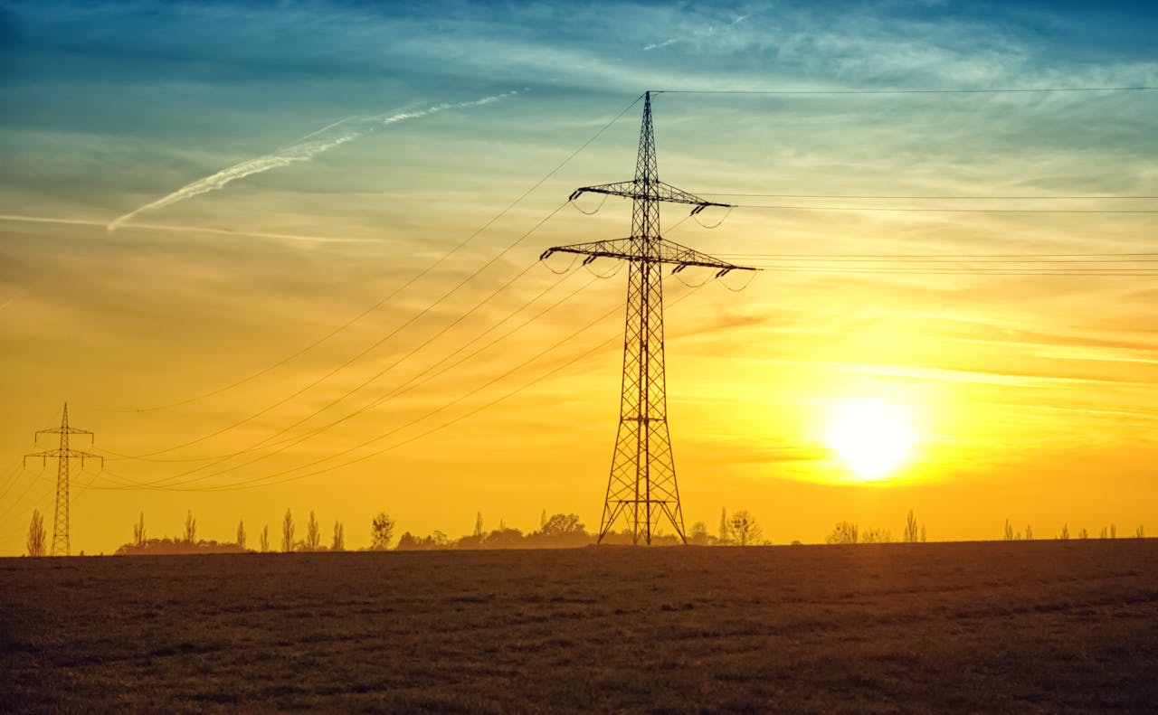 Silhouetted power lines stretch against a dramatic sunset sky, symbolizing energy and tranquility.